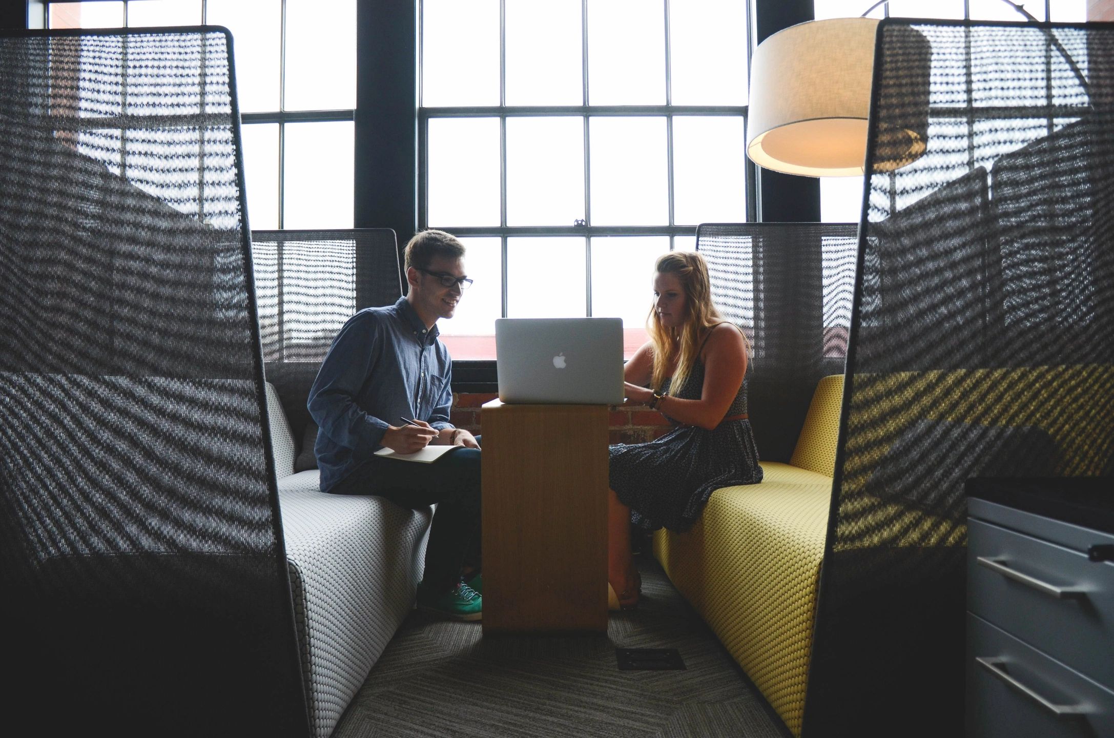 Two colleagues collaborating in a sensory-considerate, low-stimulation office booth designed for neurodiverse-friendly communication